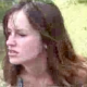 A low-quality video clip featuring an attractive brunette woman observed pooping in a natural setting outdoors.
